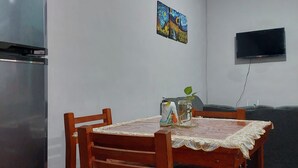 Uma sala de jantar com mesa de madeira, cadeiras e uma geladeira.