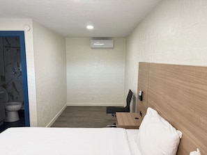Habitació d'hotel amb llit, escriptori, cadira, vàter i aire condicionat.