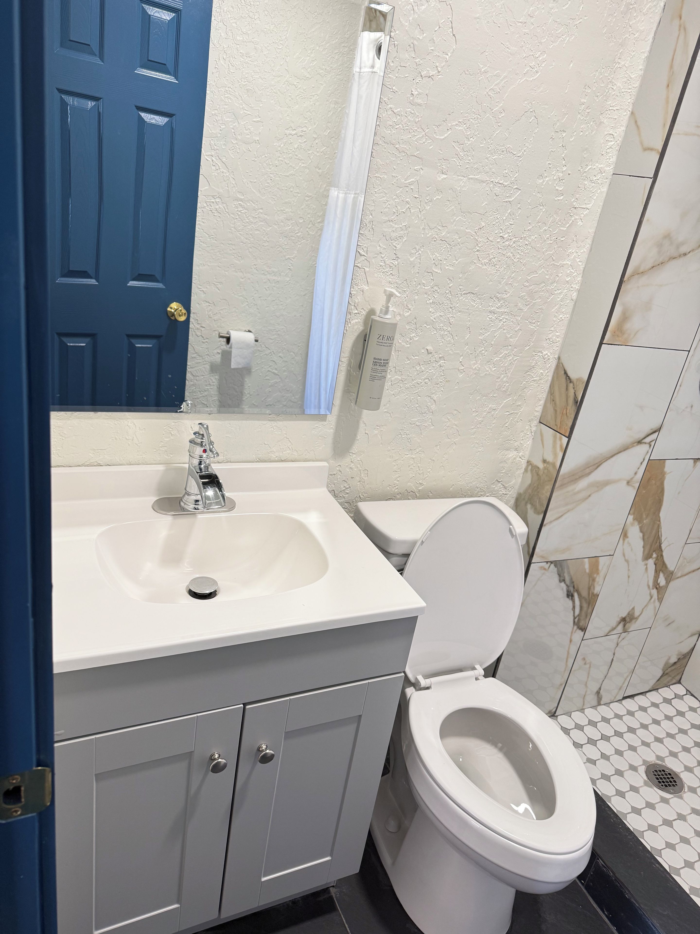 Un baño con un lavamanos blanco, un inodoro y una puerta azul.