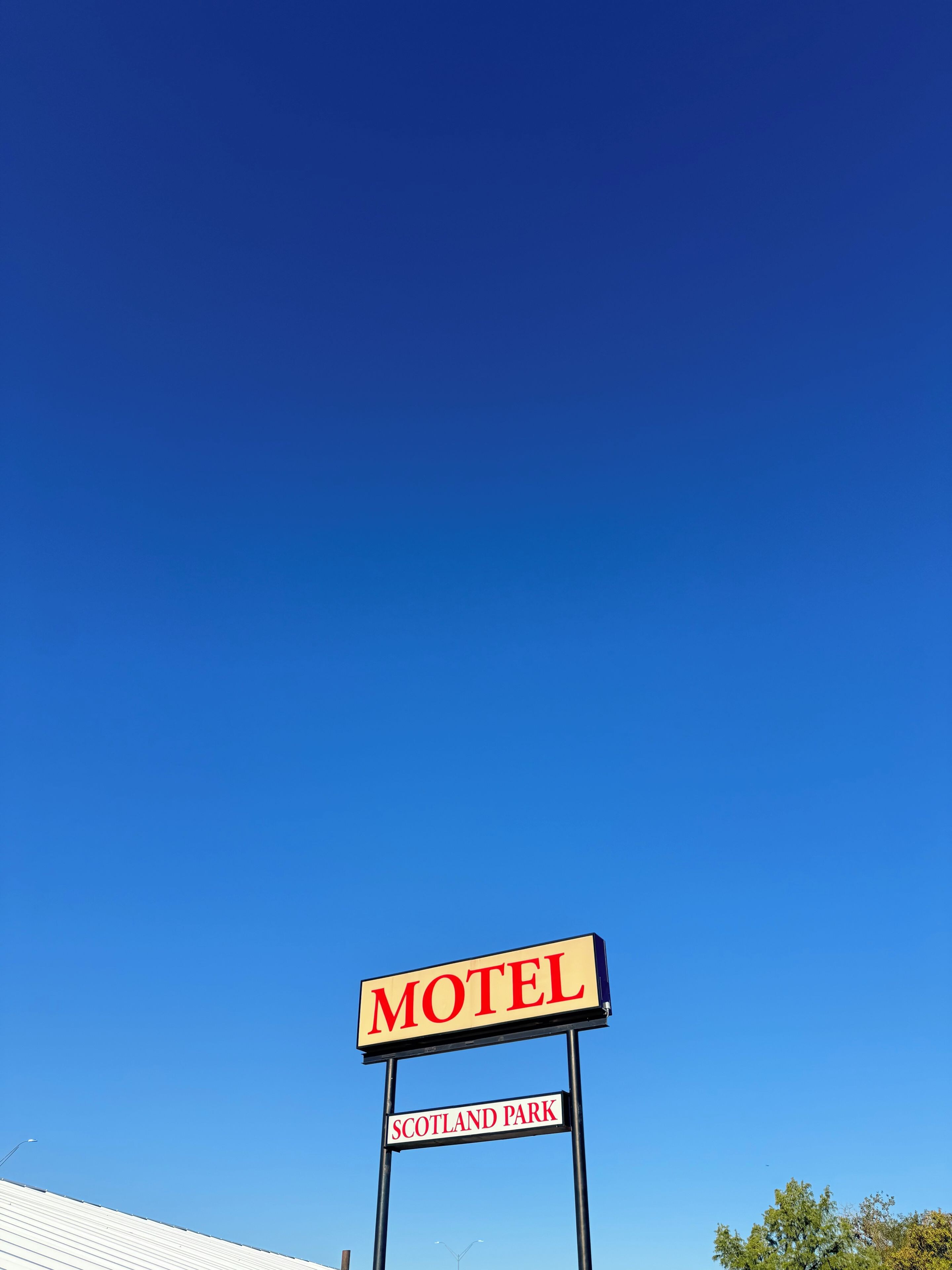 Señal de motel con la palabra 'MOTEL' y 'SCOTLAND PARK' escritas.