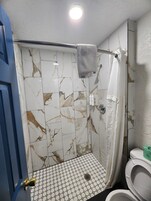 Un baño con ducha, inodoro y barra para toallas.