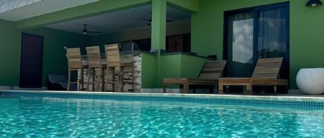 Una piscina con sillas de descanso y un porche cubierto.