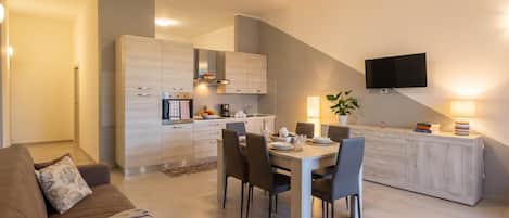 Eine moderne Küche mit Essbereich, einem flachbildfernseher an der Wand und einem Sofa im Wohnzimmer.
