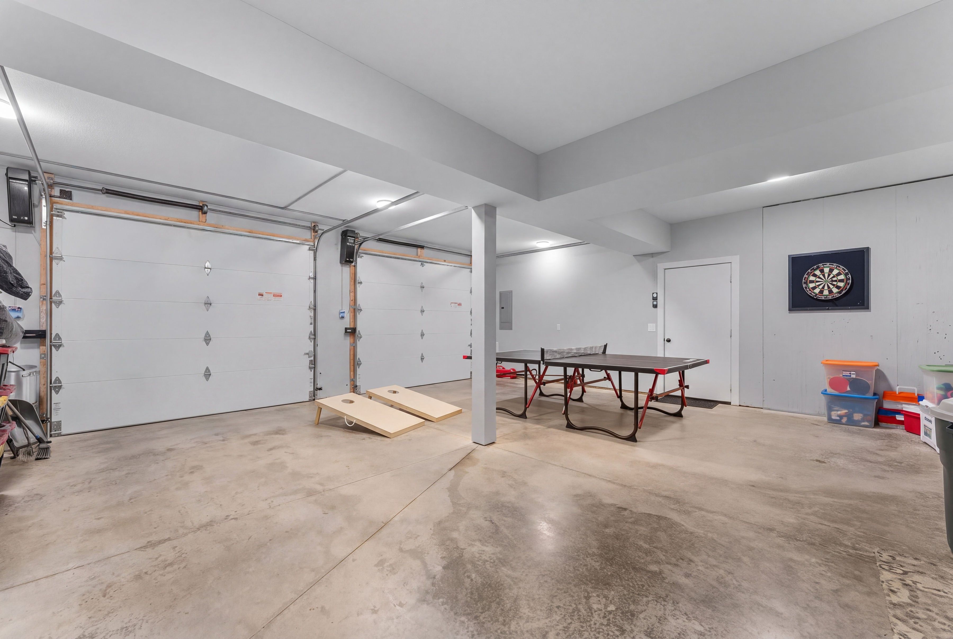 A spacious indoor area with a ping pong table, two dartboards, and a storage unit with bins.