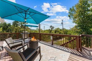 Eine Terrasse im Freien mit Feuerstelle, Sitzgelegenheiten und einem großen Sonnenschirm.