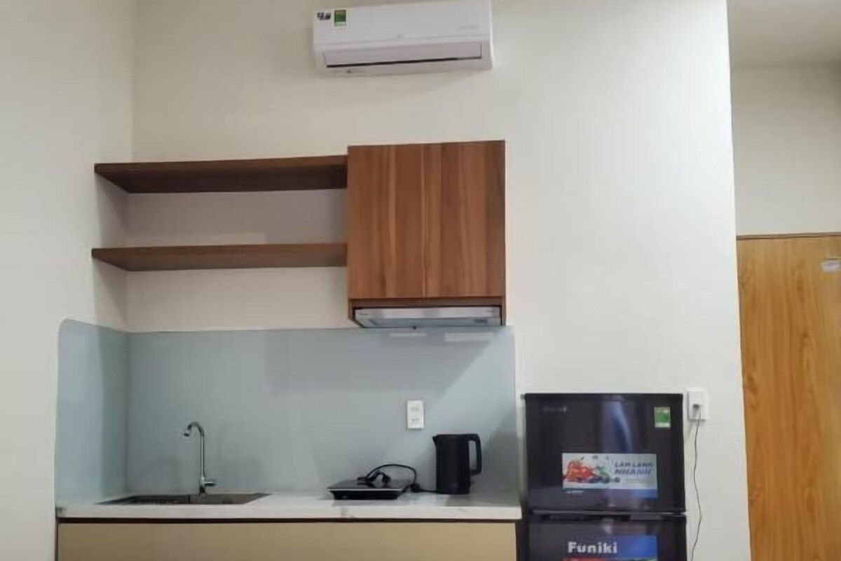 A compact hotel room with a bed, kitchenette, and a small refrigerator.