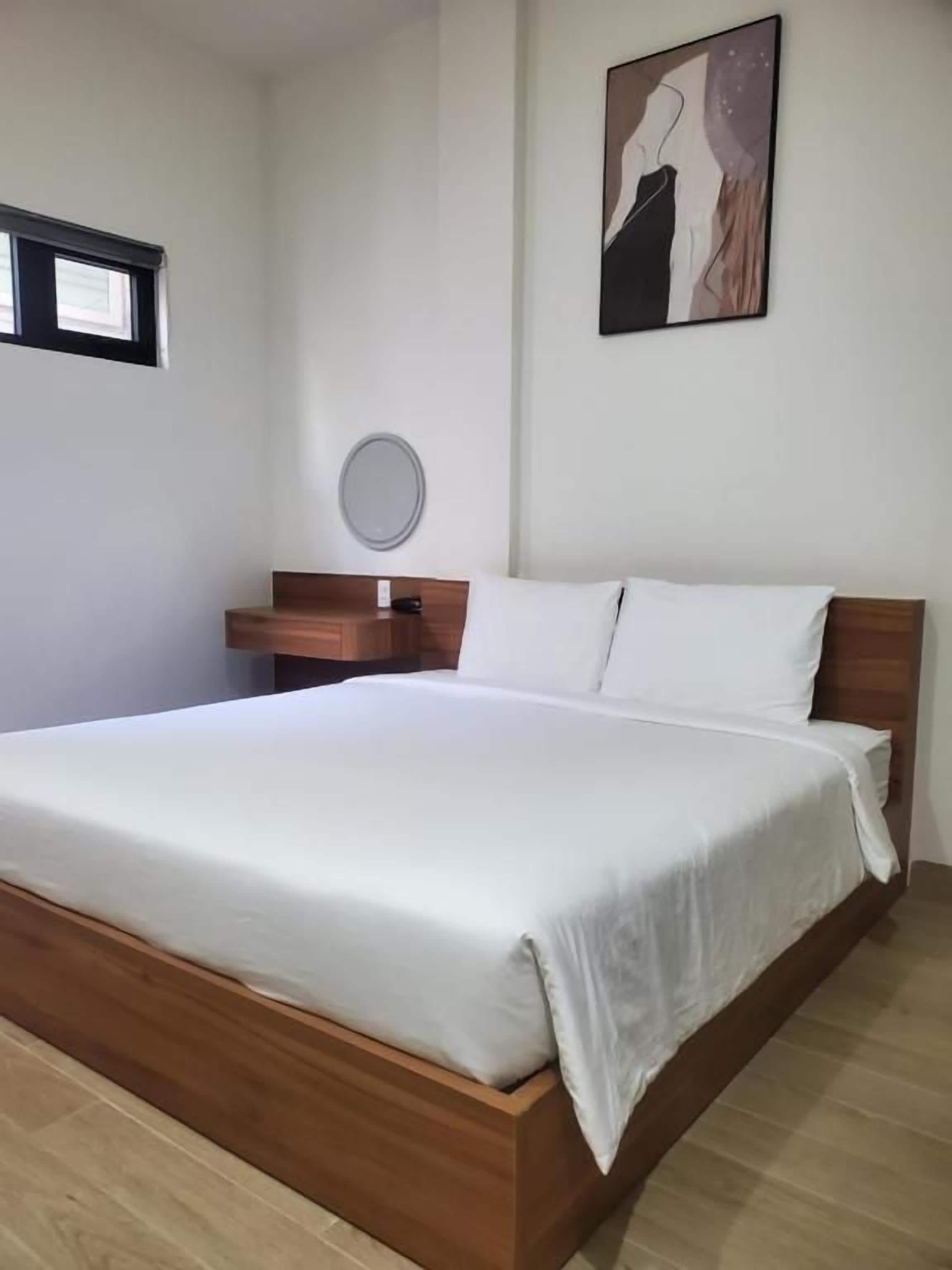 A standard hotel room with a single bed, a bedside table, a mirror, and a wall-mounted artwork.