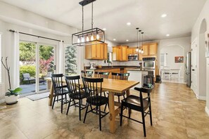 A spacious kitchen with wooden cabinets, a central island, and a dining area with chairs. - Bring everyone. Stay awhile. Make some memories! (Orem)