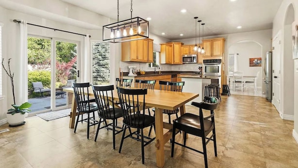A spacious kitchen with wooden cabinets, a central island, and a dining area with chairs. - Parkside 4-BR – Game Room, Waffles, Pets OK (Orem)