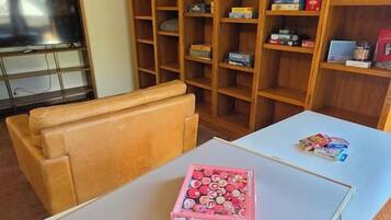A living room with a sofa, a coffee table with a box of chocolates, and a bookshelf with various items.