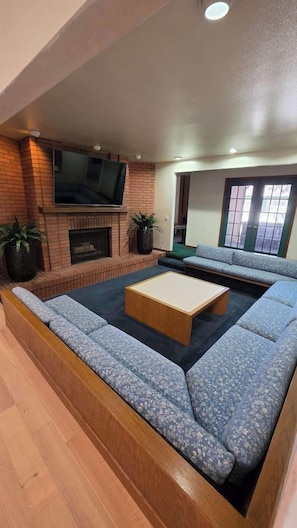 A living room with a brick fireplace, a flat-screen TV, a sofa, and a coffee table.