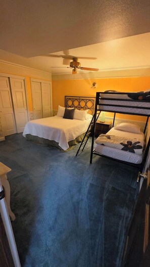 A bedroom with two beds, a ceiling fan, and a door.