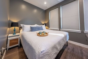 Quarto com cama grande, mesa de cabeceira com abajur e bandeja com itens de café da manhã.