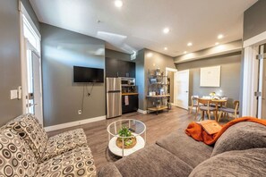 Uma sala de estar moderna com sofá, mesa de centro e área de jantar com cadeiras e mesa.