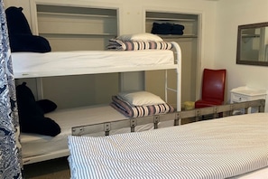 A bunk bed room with a lower bunk and a top bunk, a red chair, a small table, and a mirror on the wall. - The Nook – Stylish Basement Stay - Waffles too! (Orem)