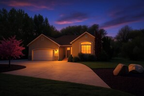 A residential house with a garage, a driveway, and a well-maintained lawn. - The Nook – Stylish Basement Stay - Waffles too! (Orem)