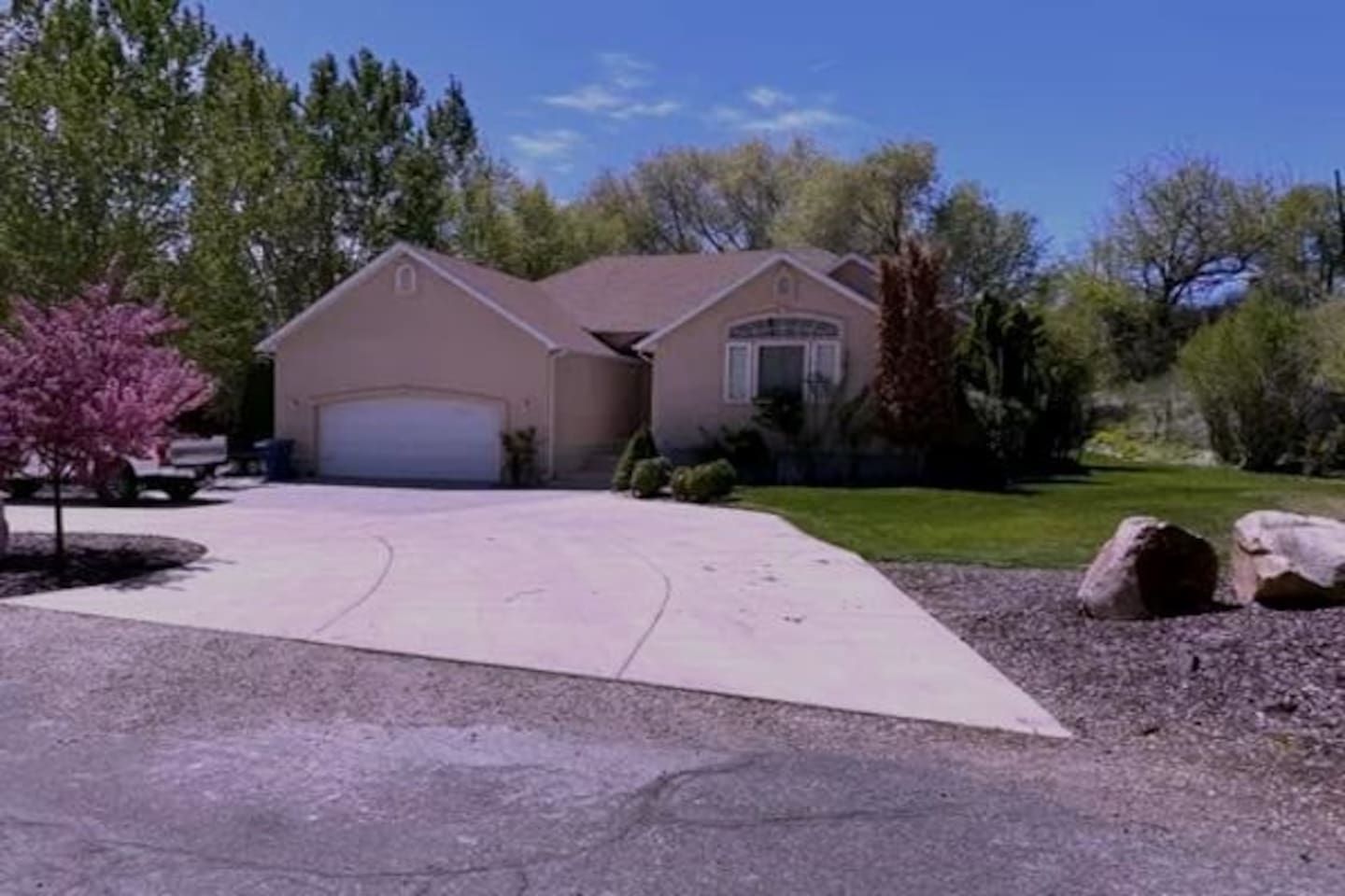 A residential house with a garage, driveway, and surrounding trees.