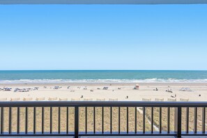 A beach view from a balcony with a railing, sandy beach, and ocean. - Wake Up to the Waves | Sea Winds 3BR (North Myrtle Beach)