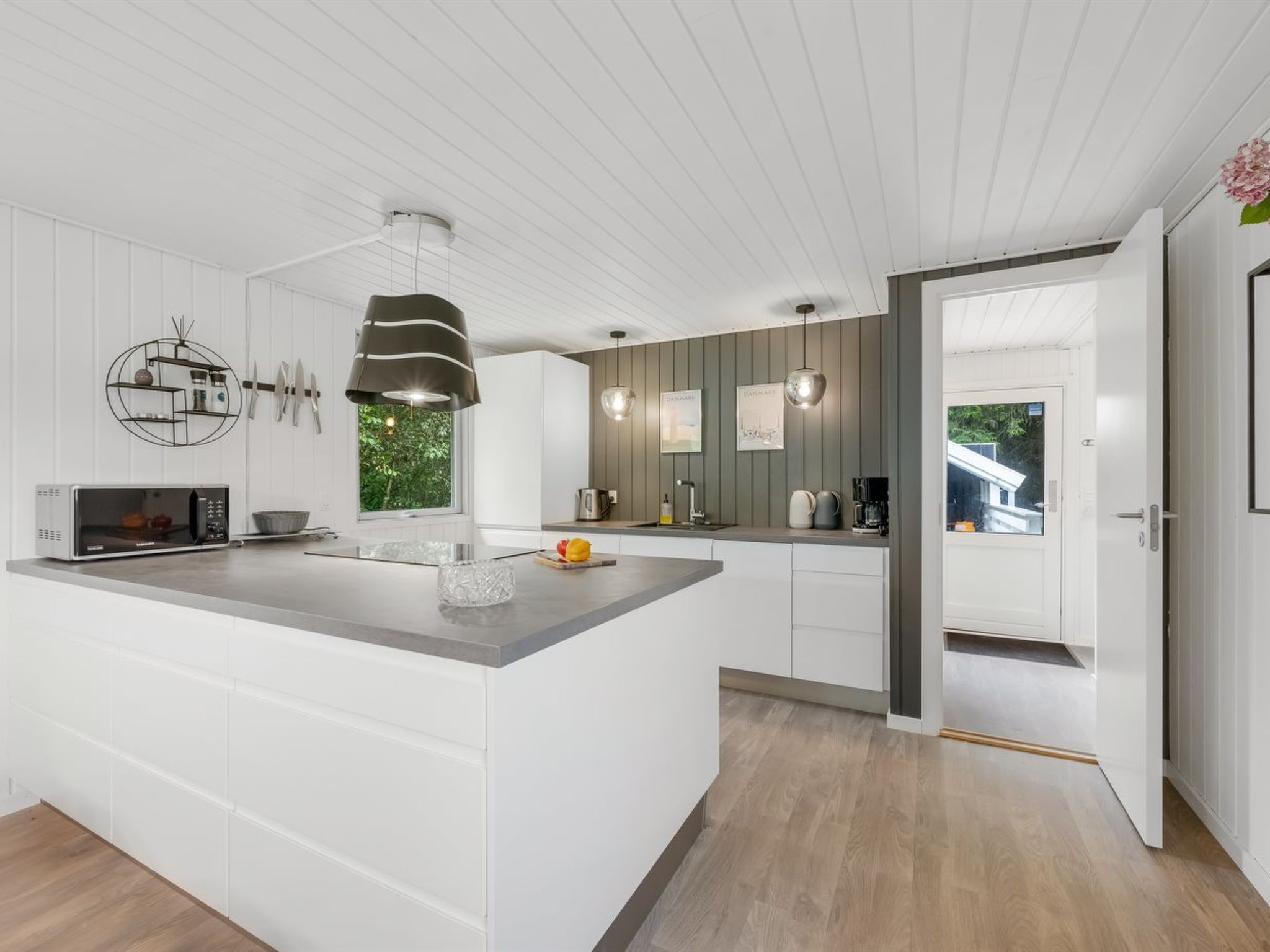 A modern kitchen with a large island, white cabinetry, and a view of the outdoors.