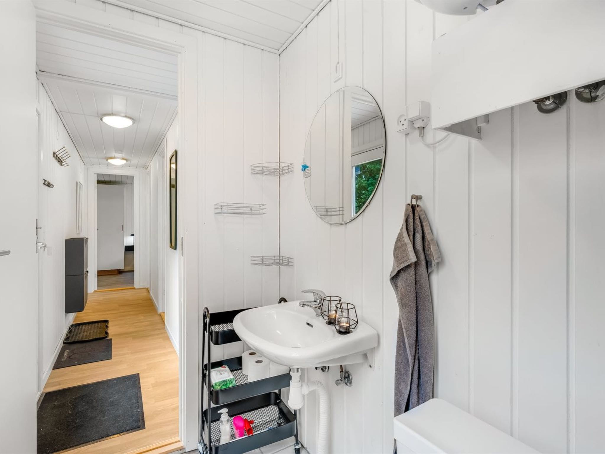A modern bathroom with a white sink, mirror, and towel rack.
