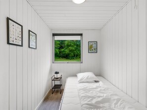 A bedroom with a bed, a desk, and a window with a view of greenery. - "Hubert" - 450m to the fjord by Interhome (Vemb)