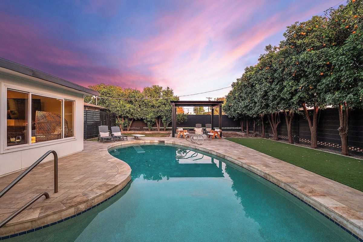 Une piscine avec un espace patio, une pergola et une pelouse bien entretenue.