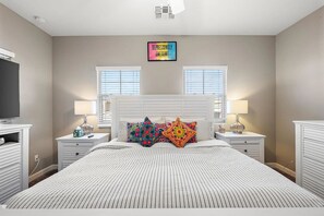 A bedroom with a large bed, two bedside tables, a TV, and a wall-mounted light fixture. - Mesa Country Club Townhome 🌵⛳ Heated Pool, Jacuzzi & Gym Near Sloan Park (Mesa)