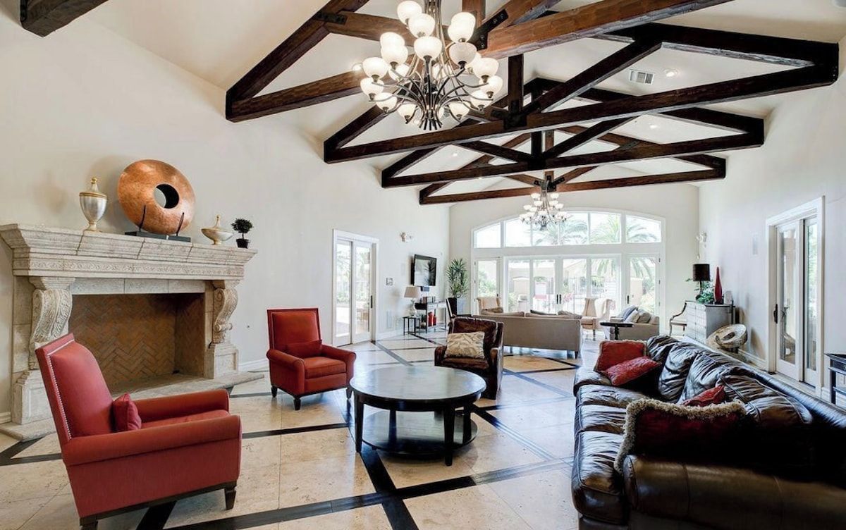 A spacious living room with a fireplace, leather sofas, and a chandelier.