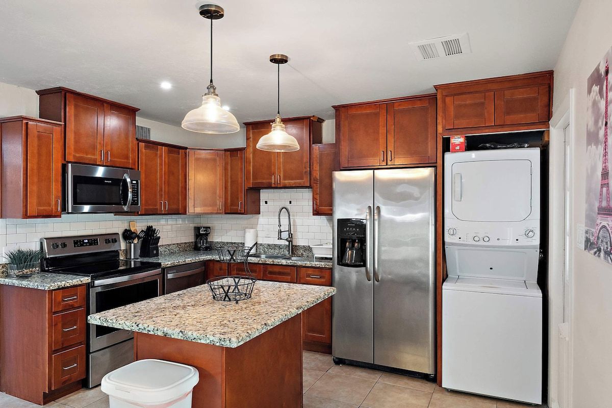 A kitchen with wooden cabinets, stainless steel appliances, granite countertops, and pendant lighting.
