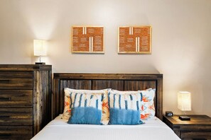 A bedroom with a wooden headboard, a bed with patterned pillows, a nightstand with a lamp, and two wall-mounted artworks. - Scottsdale Hearn Hideaway 🌵⛳ Heated Pool, Jacuzzi & Kiva Fireplace (Scottsdale)