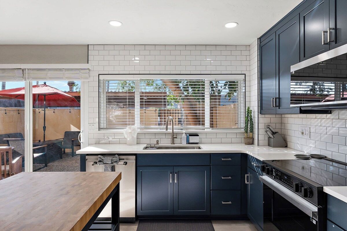 A modern kitchen with dark cabinets, a white countertop, and a large window.