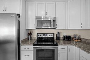 A kitchen with white cabinets, a stainless steel refrigerator, a microwave, an oven, and a toaster. - Scottsdale Old Town Lewis 🌵⛳ Private Hot Tub Near Old Town & the Zoo (Scottsdale)
