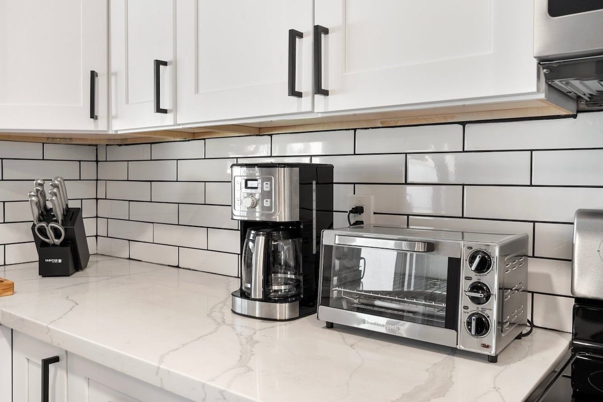 A kitchen with white cabinets, a coffee maker, and a toaster.