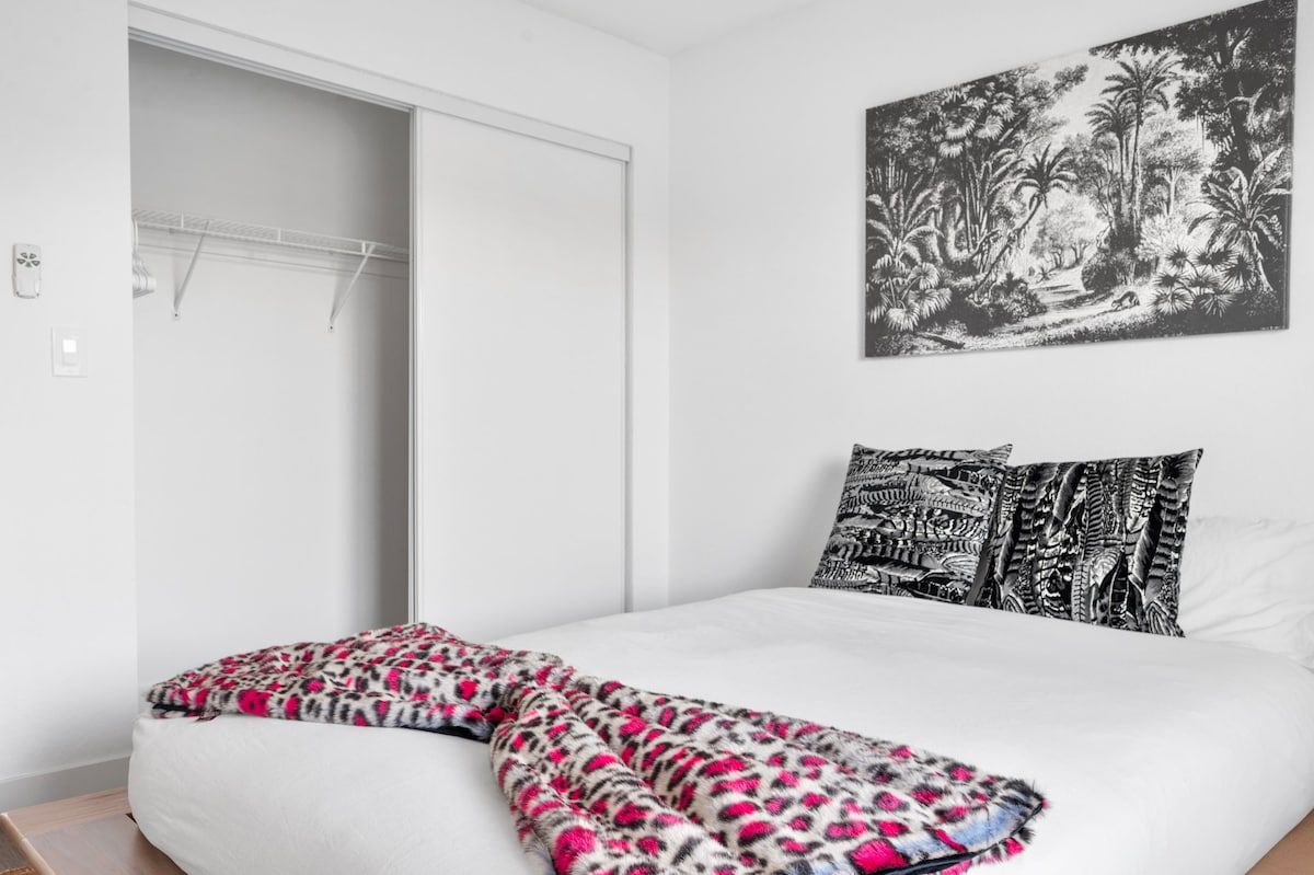 A bedroom with a bed, a wardrobe, and a wall-mounted artwork.