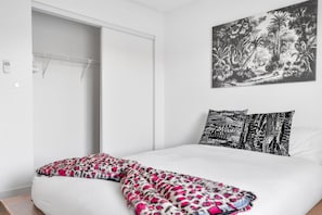Un dormitorio con cama, armario y una obra de arte en la pared.