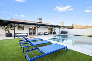 A modern outdoor pool area with blue lounge chairs, a covered seating area, and a white building with large windows. - Scottsdale Andora Retreat 🌵⛳ Heated Saltwater Pool Near Kierland Commons (Phoenix)