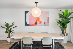 A dining area with a wooden table, grey chairs, a hanging light fixture, and two potted plants. - Scottsdale Andora Retreat 🌵⛳ Heated Saltwater Pool Near Kierland Commons (Phoenix)