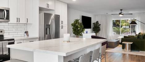 Una cocina moderna con armarios blancos, electrodomésticos de acero inoxidable y una isla grande con taburetes de bar.