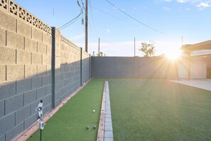 A courtyard with a brick wall, a green lawn, and a wooden fence. - Scottsdale Oasis Manor 🌵⛳ Heated Pool, Putting Green Near Old Town (Scottsdale)