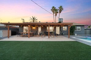 A backyard with a covered patio, outdoor furniture, a swimming pool, and palm trees. - Scottsdale Oasis Manor  🌵⛳ Heated Pool, Putting Green Near Old Town (Scottsdale)