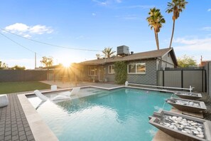 A swimming pool with a patio area, a house with a sloped roof, and palm trees in the background. - Scottsdale Oasis Manor 🌵⛳ Heated Pool, Putting Green Near Old Town (Scottsdale)