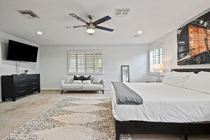 A bedroom with a bed, a sofa, a TV, a ceiling fan, and a window with blinds. - Old Town Escape 🌵⛳ Free Heated Pool & Hot Tub Near Old Town Scottsdale (Scottsdale)