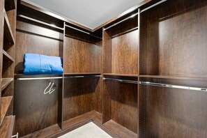 Ein begehbarer Kleiderschrank mit Holztüren, einer Kleiderstange und einem blauen Kissen.