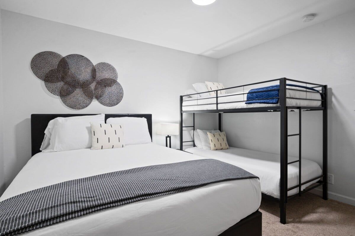 Une chambre avec un lit superposé, un lit simple et un élément décoratif fixé au mur.