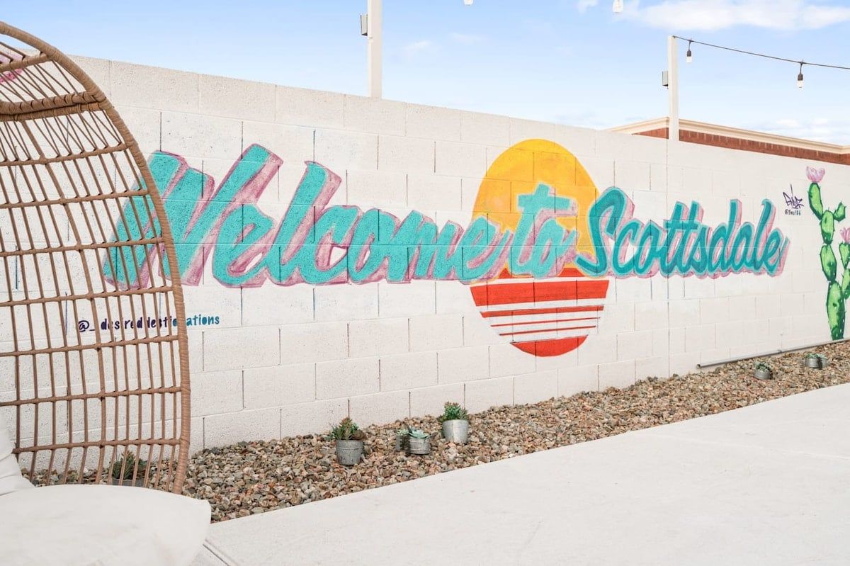 A wall with a colorful mural that reads 'Welcome to Scottsdale' and includes a cactus illustration.