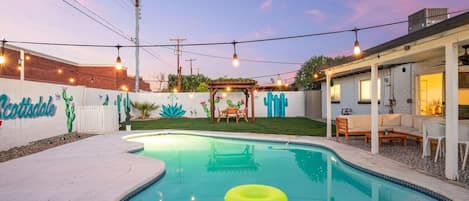 Un patio trasero con piscina, pérgola y zona de patio.