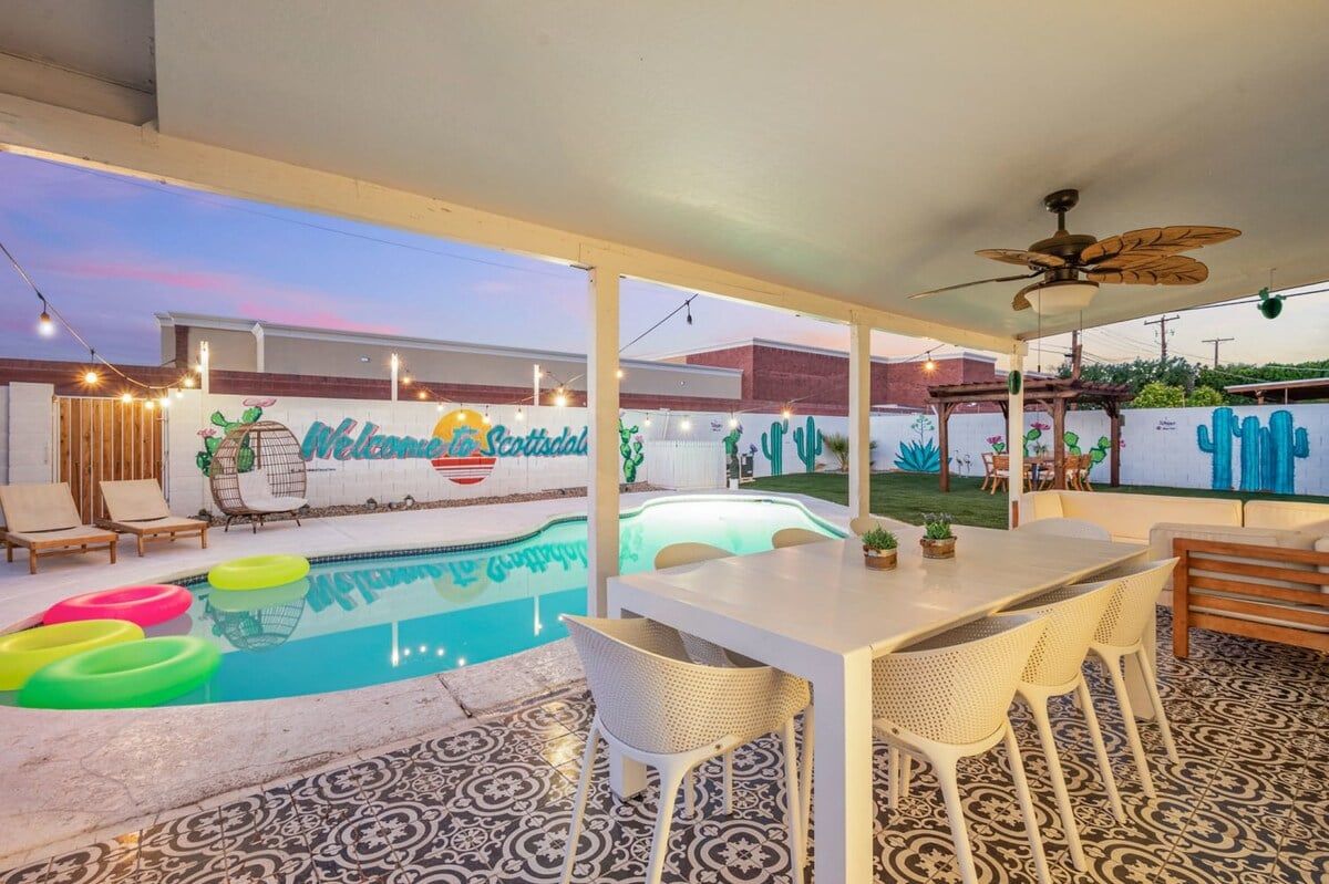 A pool area with a mural, outdoor seating, and a ceiling fan.
