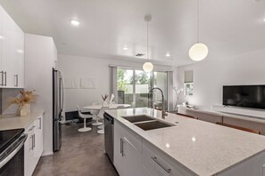 A modern kitchen with a central island, white cabinetry, and a built-in dishwasher. - Chandler Townhome 1 🌵 Walk to Downtown Chandler, Community Pool & Grill (Chandler)