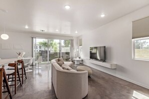 Ein modernes Wohnzimmer mit einem großen Flachbildfernseher, einer Couch und einem Essbereich mit Stühlen.