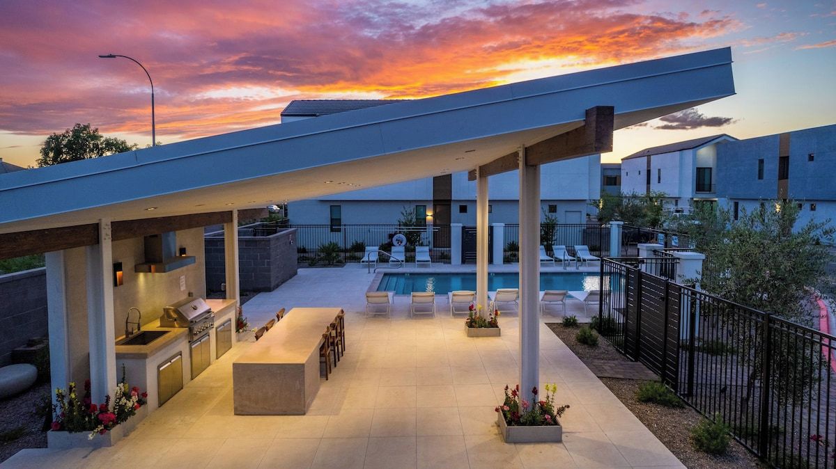 A modern outdoor patio with a pool, seating, and a covered barbecue area.